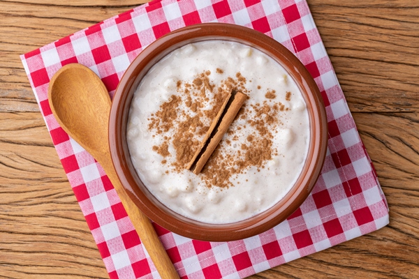 canjica or munguza typical brazilian white corn sweet cream with cinnamon over wooden table - Каша жидкая молочная рисовая (школьное питание)