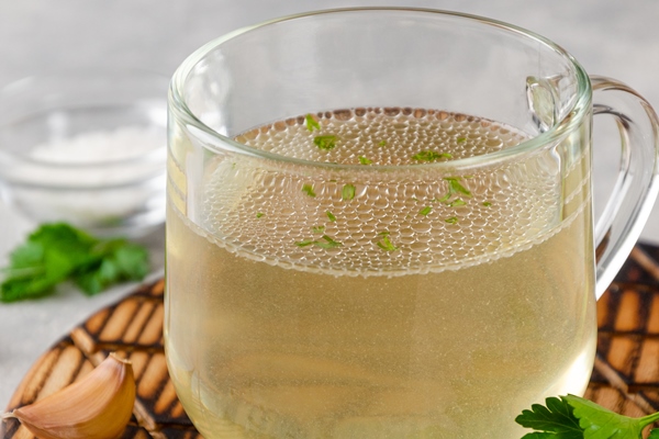 chicken broth in a glass cup with parsley garlic and other spices copy space 1 - Плов из морского гребешка