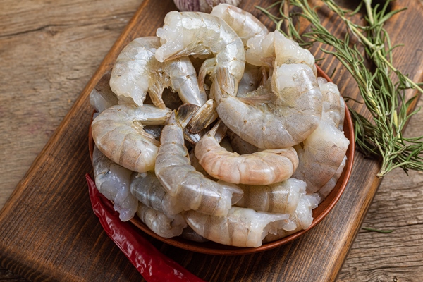 close up of raw shrimps on wooden background - Жареные креветки с чесноком