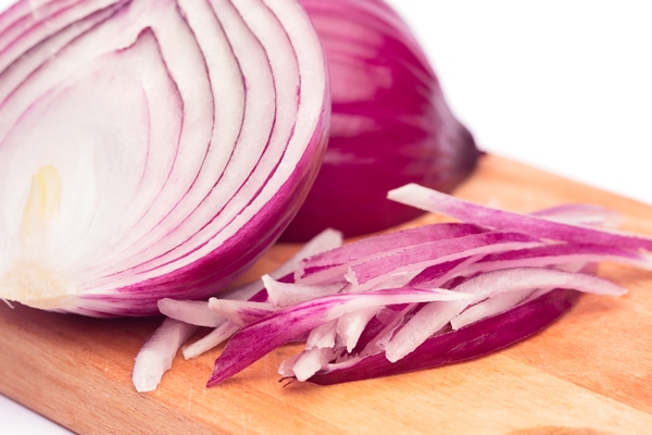 close up of sliced red onion and whole red onion on a wooden table - Фасолевый суп (школьное питание)