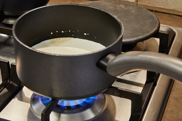 cream is cooked in saucepan on gas stove to make cake - Каша жидкая молочная пшённая (школьное питание)