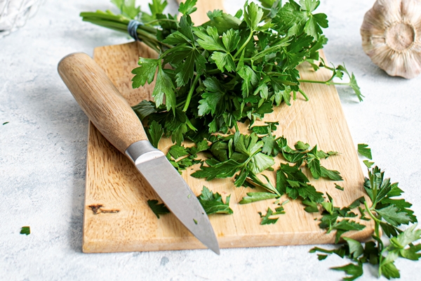 fresh organic parsley on a wooden cutting board - Чёрные спагетти с морепродуктами