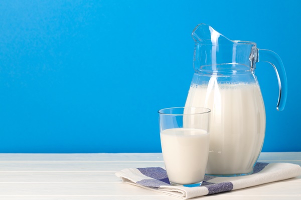 glass and pitcher of milk against blue background front view - Каша жидкая молочная рисовая (школьное питание)