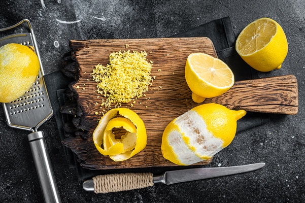 grated lemon zest and spiral peel on wooden board black background top view - Постный салат с тунцом "Новогодний"
