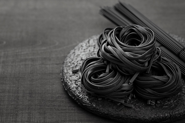 high angle of black tagliatelle on plate with spaghetti - Чёрные спагетти с морепродуктами
