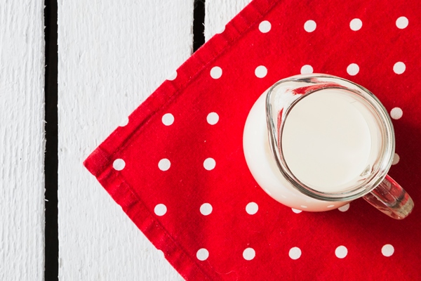 pitcher of milk on the red polka dot napkin over the white table - Суп молочный с рисом (школьное питание)