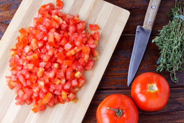 raw chopped and diced tomatoes cubes over rustic wooden table top view - Чёрные спагетти с морепродуктами