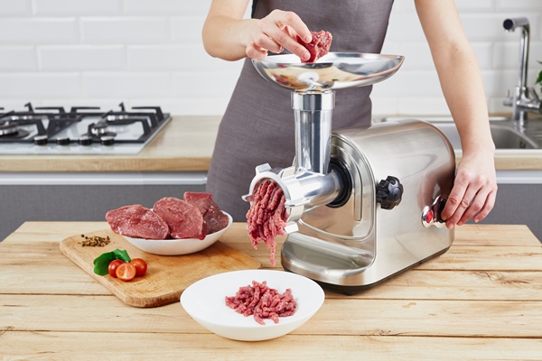 raw meat the process of preparing forcemeat by means of a meat grinder female hands use meat chopper at kitchen - Суп овощной с фрикадельками (школьное питание)