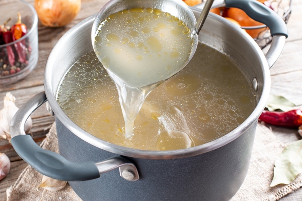 saucepan with bouillon with a ladle on the table bone broth 2 - Рассольник с рисом (школьное питание)
