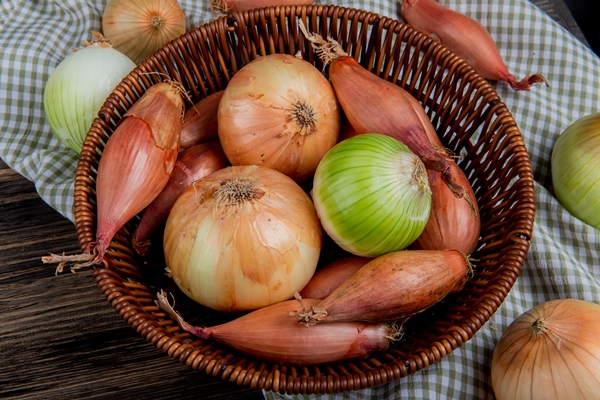 side view of onions as shallot sweet and white ones in basket on plaid cloth and wooden background - Суп крестьянский с перловой крупой (школьное питание)