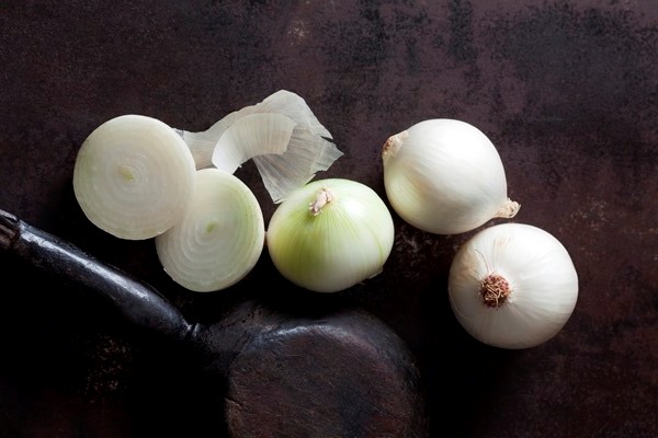 sliced and whole white onions on rusty ground - Плов из морского гребешка