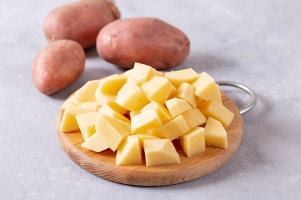 sliced potato on a cutting board on a light concrete background - Суп картофельный с макаронами (школьное питание)