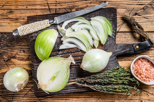 sliced raw white onion on a wooden cutting board - Суп рыбный с горбушей (школьное питание)