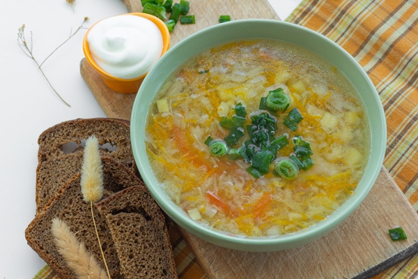 traditional soup of russia shchi with green onion served with sour cream as garnish and rye bread - Суп крестьянский с рисом (школьное питание)