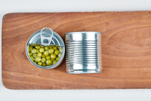 two cans of boiled green peas on a wooden board 1 - Салат "Оливье" с крабами