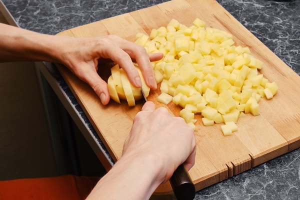 unrecognizable woman chopping chopped potatoes with a knife on cutting board - Салат "Оливье" с крабами