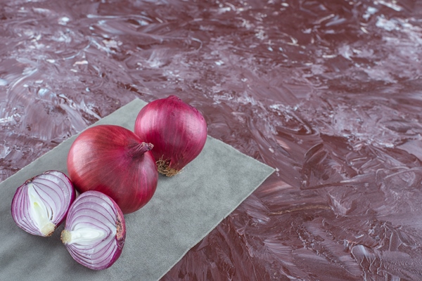 whole and sliced onion on a pieces of fabric on the marble background - Чёрные спагетти с морепродуктами