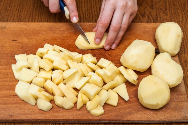 woman s hand with a knife slicing potatoes - Рассольник домашний (школьное питание)
