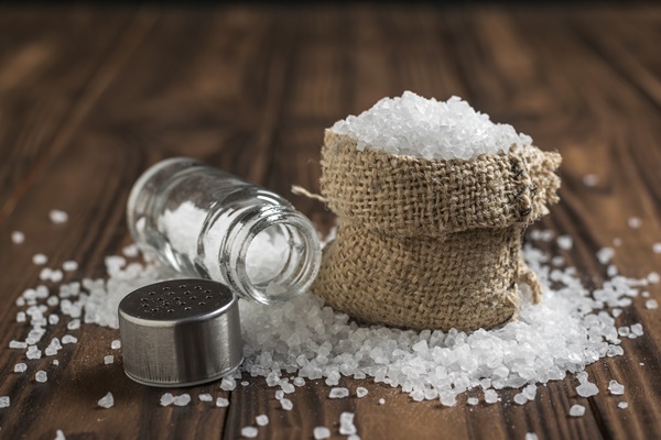 a bag of scattered salt and a glass salt shaker on a wooden table ground stone sea salt - Сметанный соус натуральный (школьное питание)