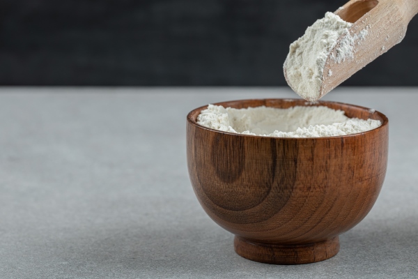 a wooden bowl of flour and wooden spoon 1 - Постные манные оладьи
