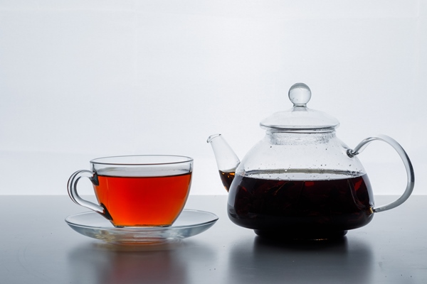 brewed tea in teapot and cup side view on a white gradient surface - Чай с лимоном и малиновым сиропом на фруктозе (диетическое школьное питание)