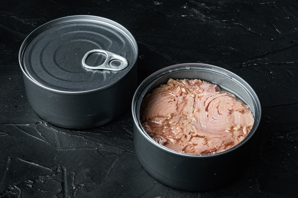 canned wild yellowfin tuna set in tin can on black background - Омлет с тунцом