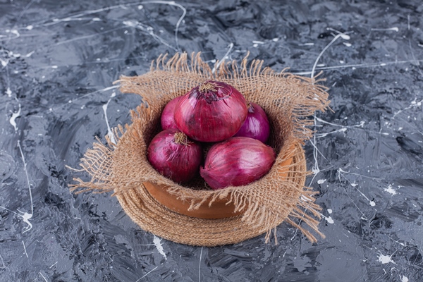 ceramic bowl of fresh red onions on blue surface - Салат из краснокочанной капусты с орехами