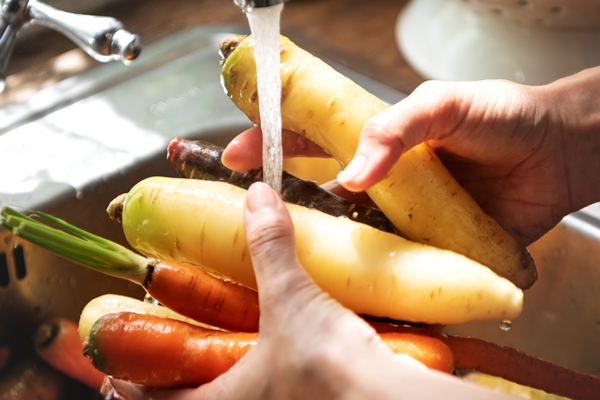 chef cleaning carrots and turnips in the sink - Рыба, запечённая в томате с овощами (школьное питание)