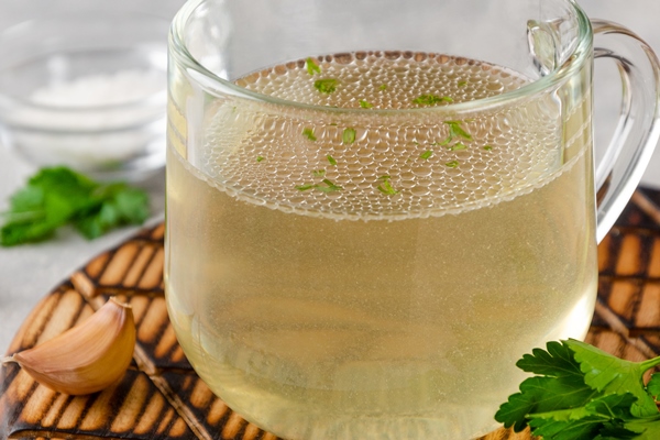 chicken broth in a glass cup with parsley garlic and other spices copy space - Суп пюре из лука-порея