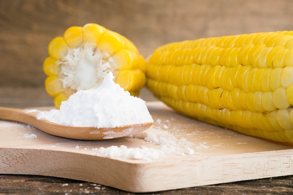 corn flour in spoon on wooden - Секреты приготовления киселей на крахмале