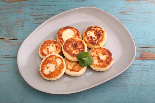 cottage cheese pancakes or syrniki on a plate decorated with mint closeup view old wood background russian ukrainian cuisine healthy tasty breakfast top view - Сырники (школьное питание)