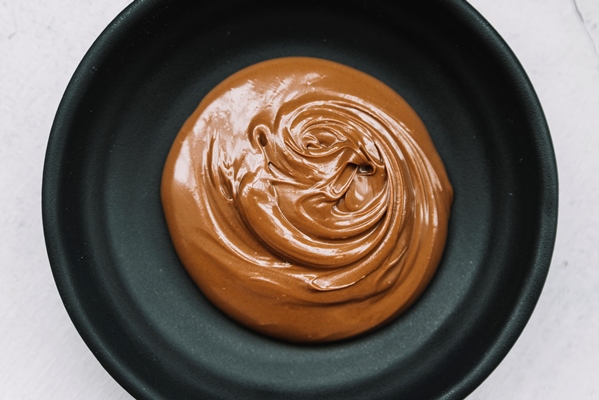 delicious melted chocolate in black bowl over white background - Соус шоколадный (школьное питание)