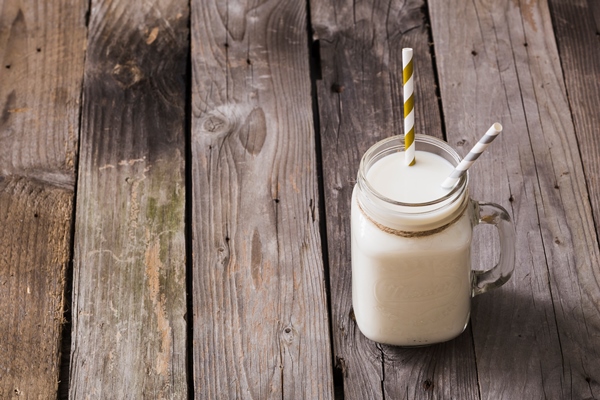 elevated view of milk jar with two drinking straws on wooden table - Секреты приготовления киселей на крахмале