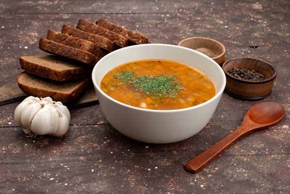 front view orange vegetable soup with bread loafs and garlic on brown food meal soup - Щи монастырские богатые