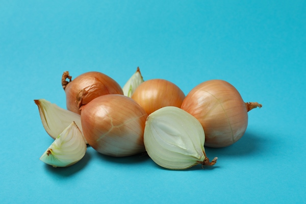 group of fresh ripe onion on blue background - Рыба, запечённая с луком и сыром (школьное питание)