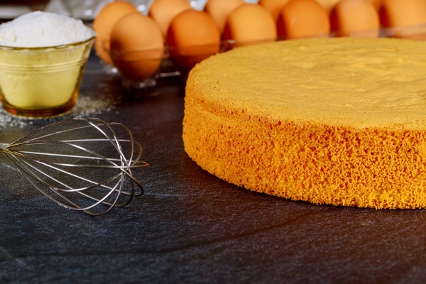 homemade sponge cake on black background with eggs flour and whisk - Морковный торт
