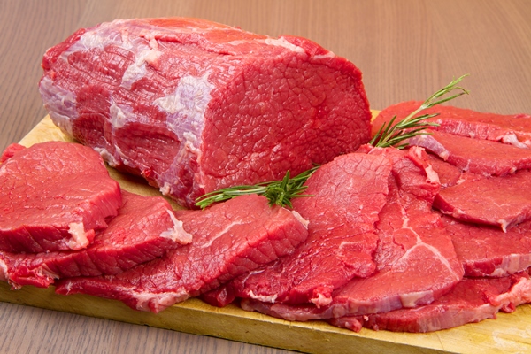 huge red meat chunk and steak on wood table - Бефстроганов из отварной говядины (школьное питание)