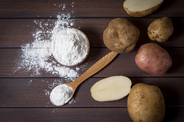 potato starch with potatoes on a dark wooden background - Секреты приготовления киселей на крахмале