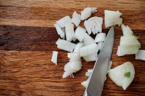 raw onion chopped very small cubes on a wooden board with a knife - Постный простой суп