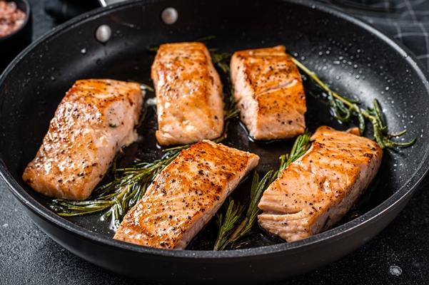 roasted salmon fillet steak in a pan with rosemary black background top view - Горбуша, запечённая в сметанном соусе (школьное питание)