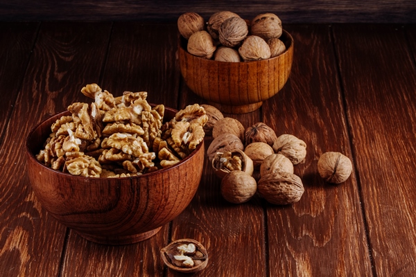 side view of walnuts in a wooden bowl on dark rustic background - Морковный торт