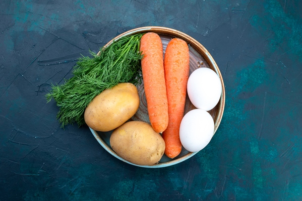 top view carrots and potatoes with eggs and greens on dark blue desk - Салат "Оливье" по-монастырски
