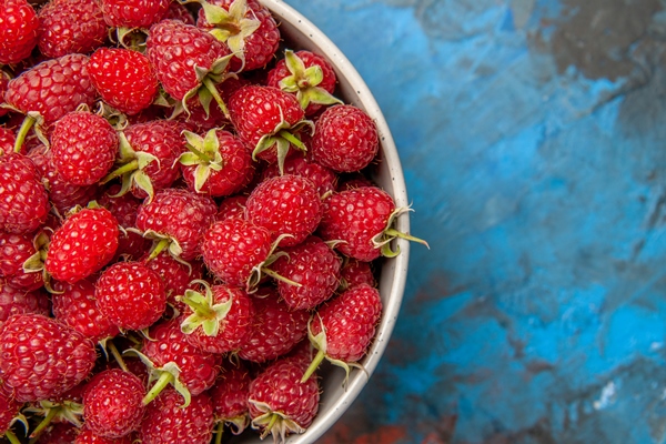 top view red raspberries inside plate on blue background - Чай с малиной и сахаром (школьное питание)