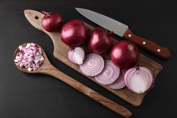 wooden board with cut and whole red onions on black surface - Соус красный основной (школьное питание)
