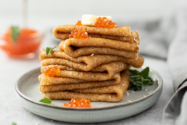 a stack of thin pancakes with red salted caviar and butter close up 1 - Налитки