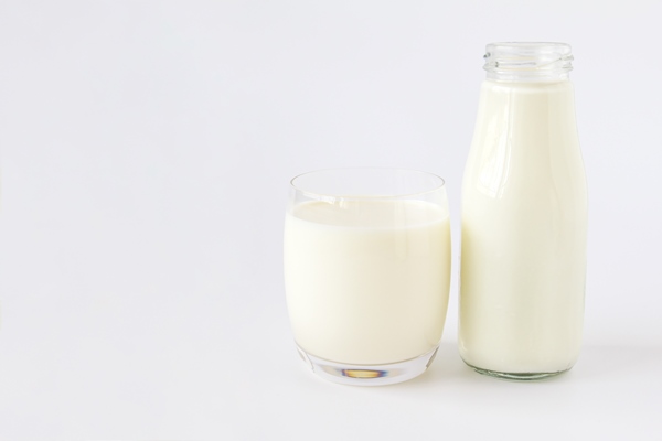 bottle of milk and glass of milk on a white background - Овсяная каша с кэробом, инжиром и бананом
