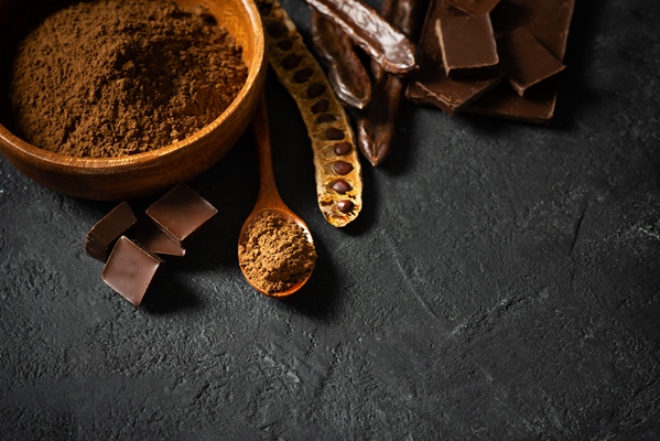 carob bean and powder in bowl flat lay on black background top view copy space - Пирожное "Картошка" с кэробом