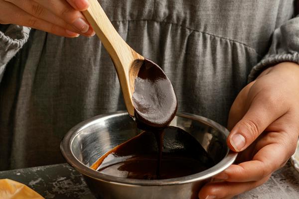 close up hand holding wooden spoon with chocolate - Постный пудинг с кэробом