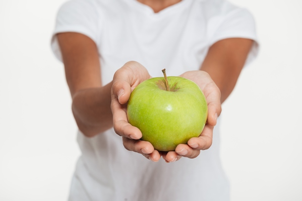 close up of female hands showing green apple - Оладьи яблочные дрожжевые, постный стол