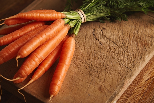 close up shot of a bunch of fresh ripe carrots on an old chopping board with deep cuts - Суп с фрикадельками из шампиньонов или вешенок